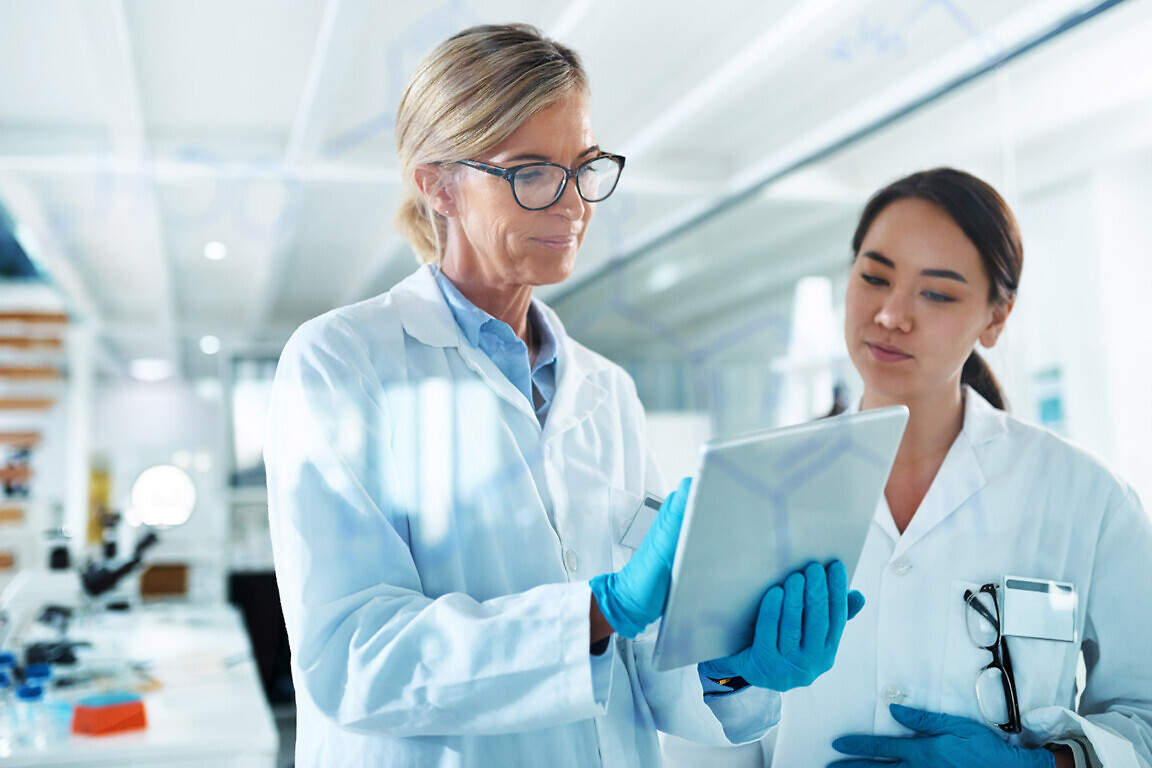 Women, scientist and discussion with tablet by glass, reading and review with results at pharma company. People, mentor and feedback with notes, application and medical research for mpox vaccine