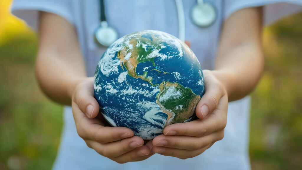 A child's hands holding a globe, wearing a stethoscope around their neck, symbolizing healthcare and the planet.