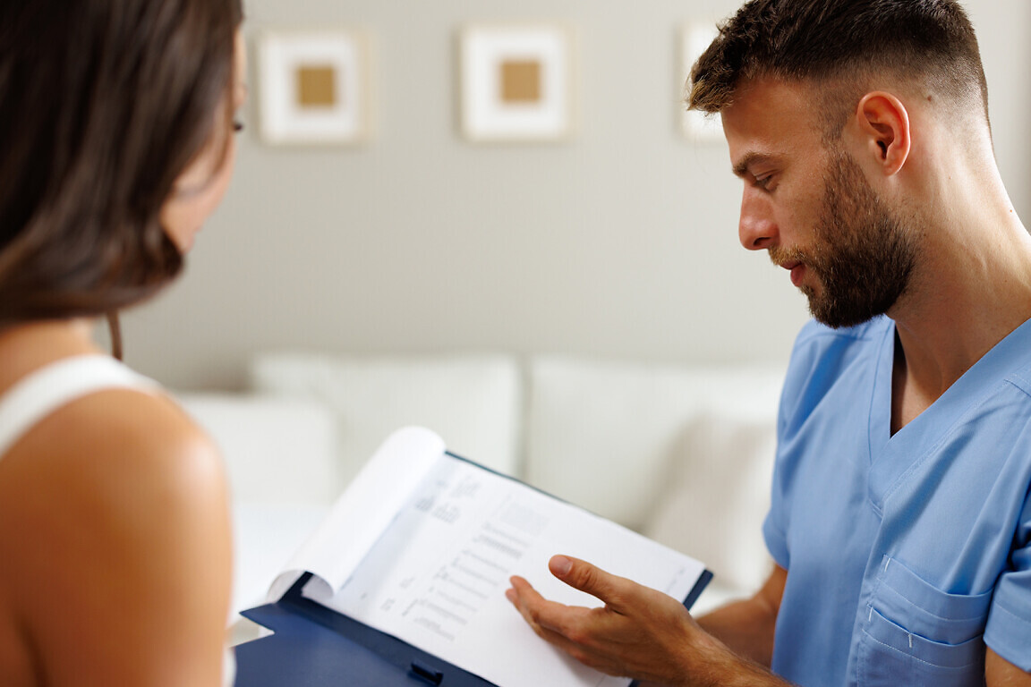 Healthcare professional showing medical records to female patient during consultation