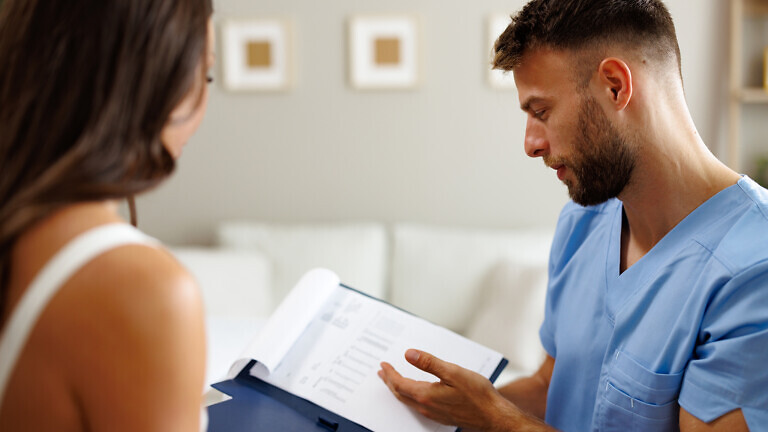 Healthcare professional showing medical records to female patient during consultation