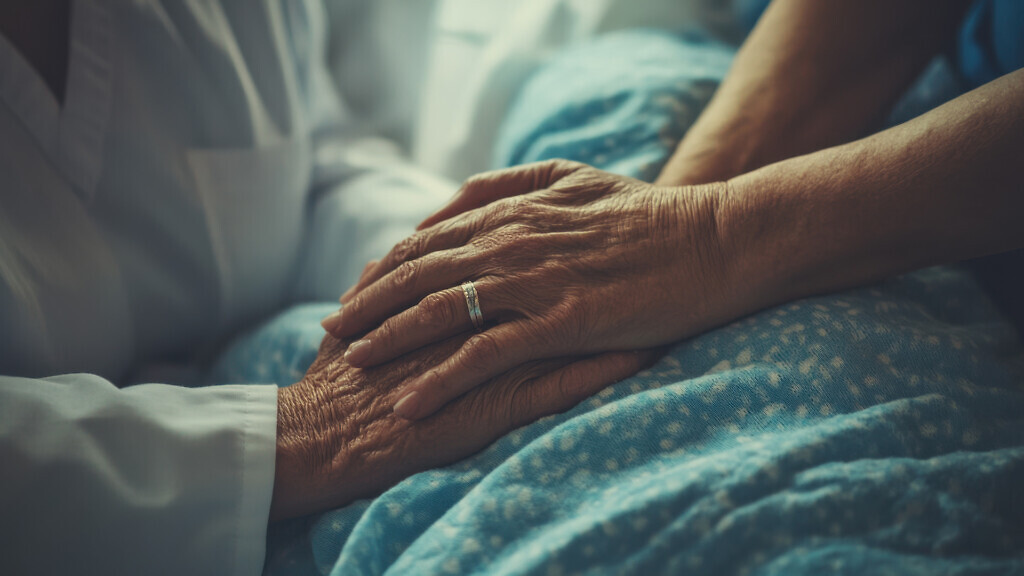 The caring hands of a nurse comforting a terminally ill patient