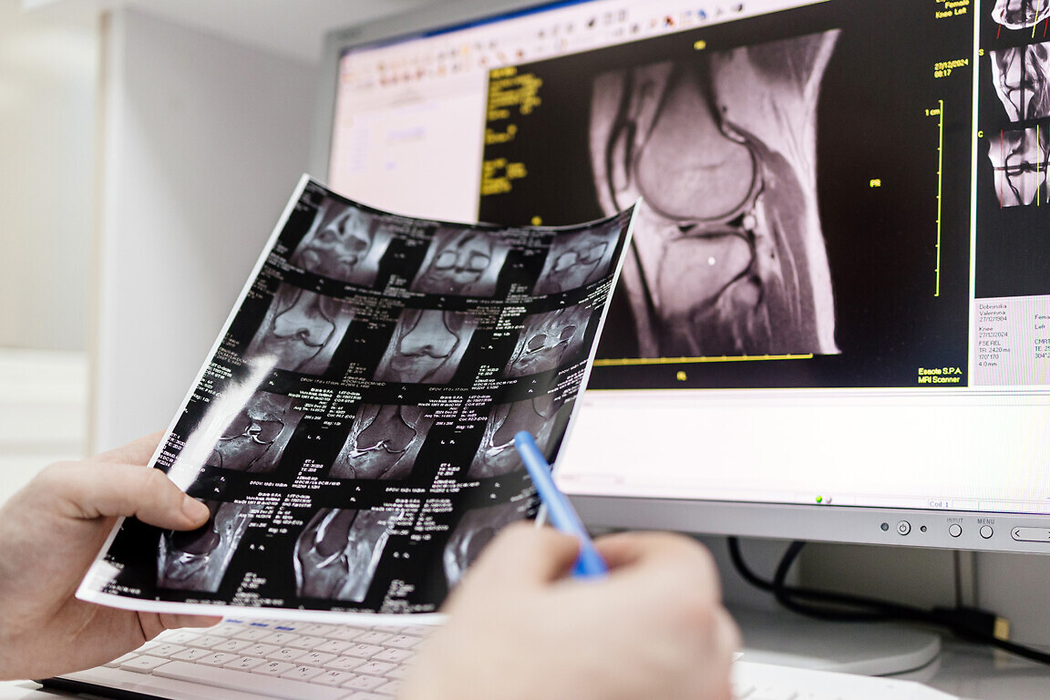 A doctor examines MRI scans in the MRI control room of a modern hospital.