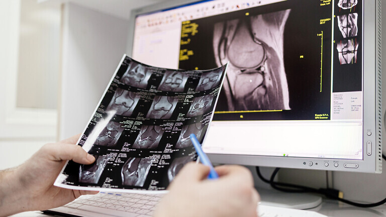 A doctor examines MRI scans in the MRI control room of a modern hospital.