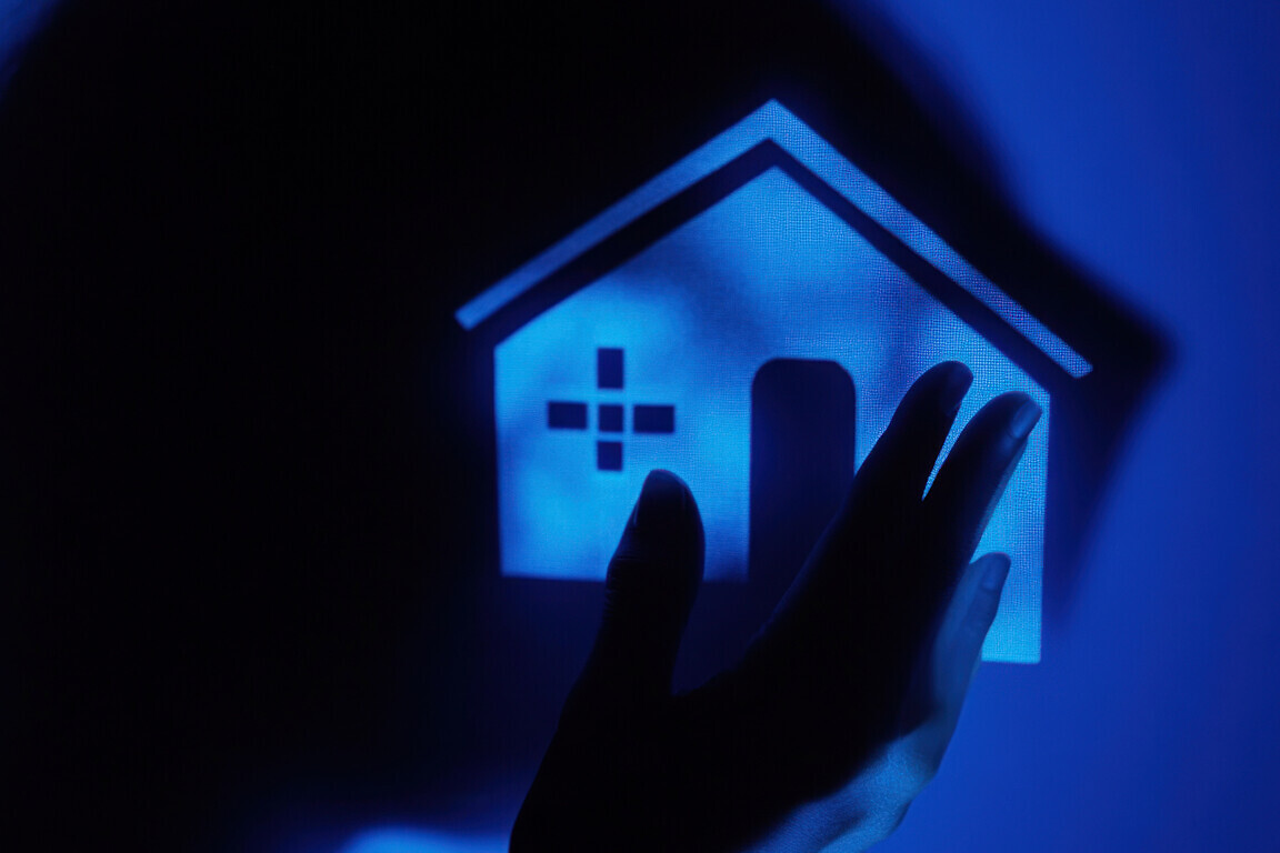 Hand holding glowing house icon, healthcare concept.