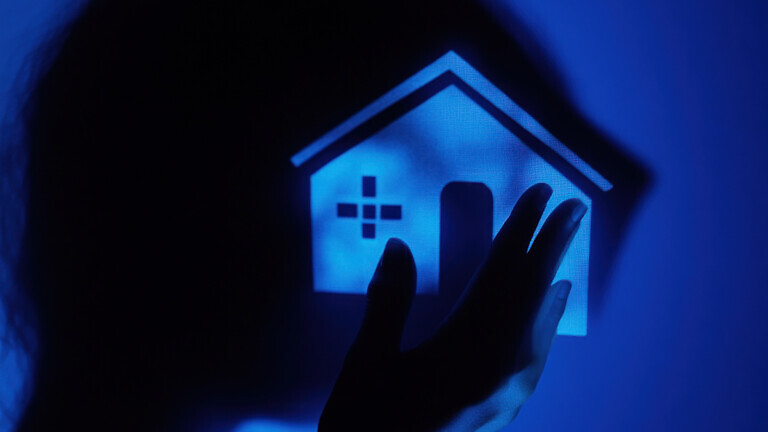 Hand holding glowing house icon, healthcare concept.