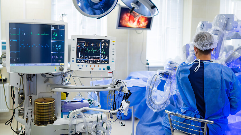 Surgeon in advanced surgery. A skilled surgeon is focused on a complex procedure inside a sterile operating room, surrounded by high-tech equipment.