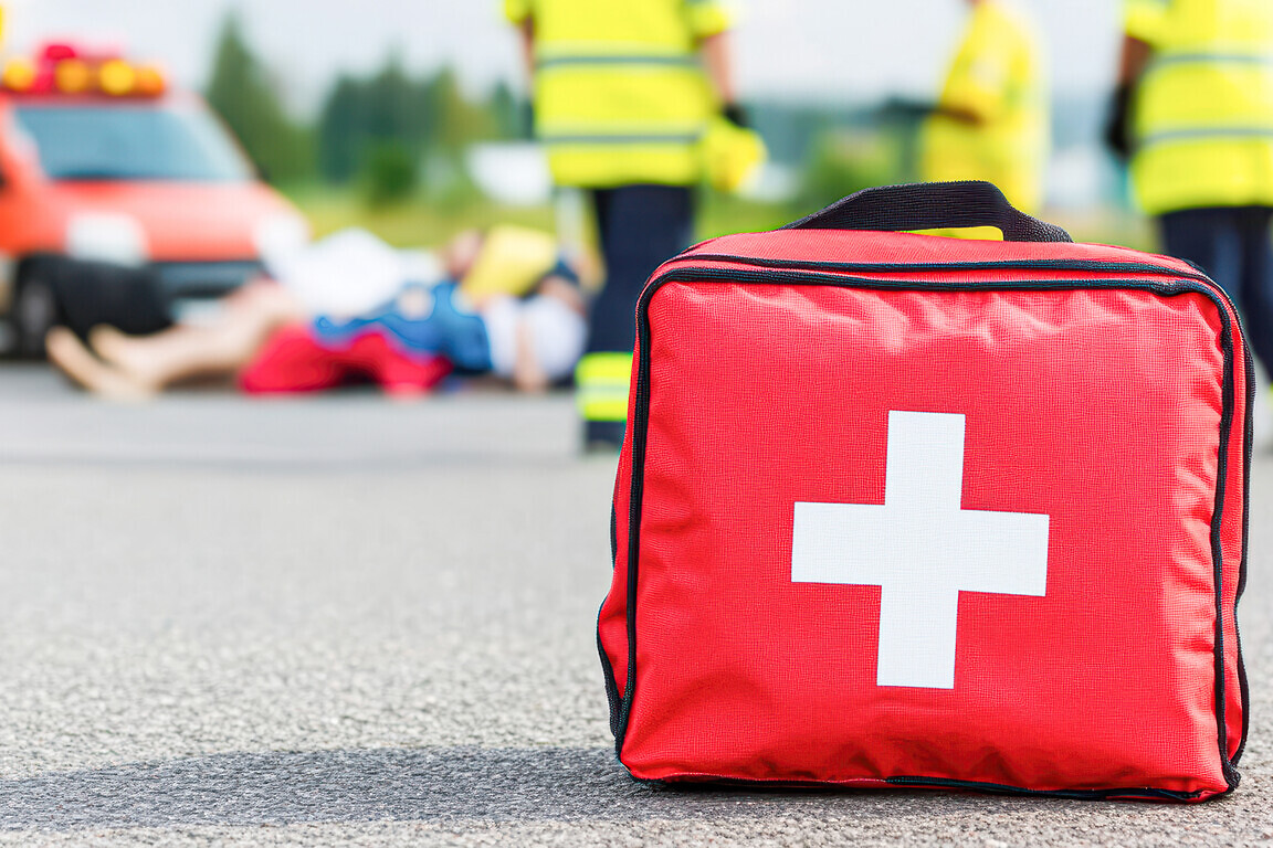 First aid kit near emergency responders at an accident scene.