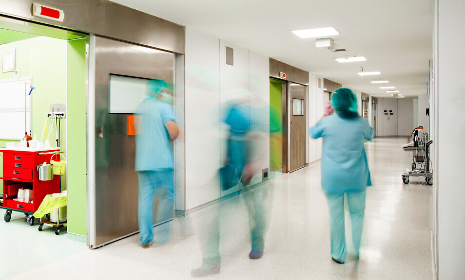 Blurred figures of doctors and nurse down the corridor in surgery section of a modern hospital.