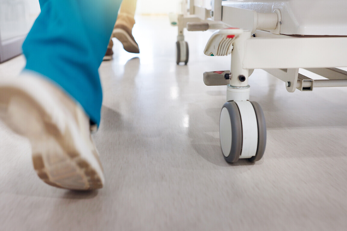 Running, hospital and doctors with stretcher for emergency, surgery and ICU help. Healthcare, medical service and feet of people rush with bed for accident, operation or surgical treatment in hallway