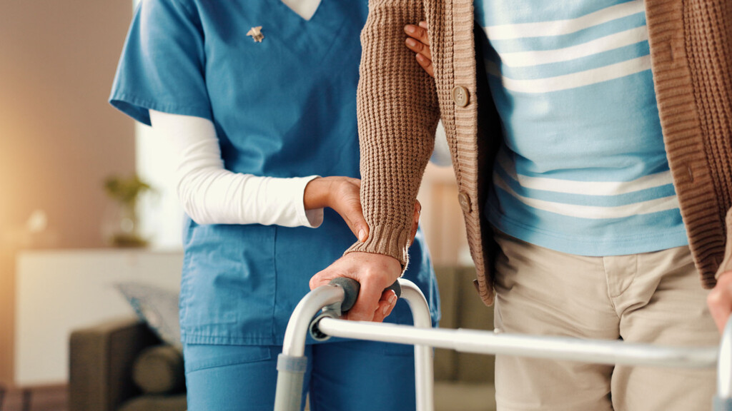 Hands, shoulder and nurse with senior person on sofa for comfort, empathy and support. Retirement home, healthcare and caregiver with patient for medical care, help and compassion in assisted living