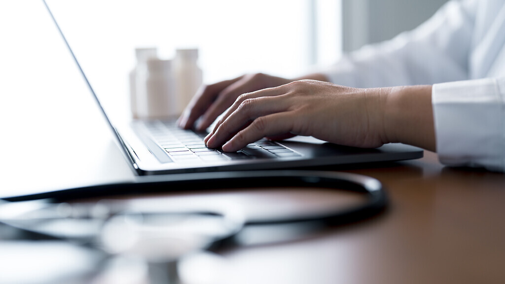 Close-up hands of doctor typing on laptop keyboard