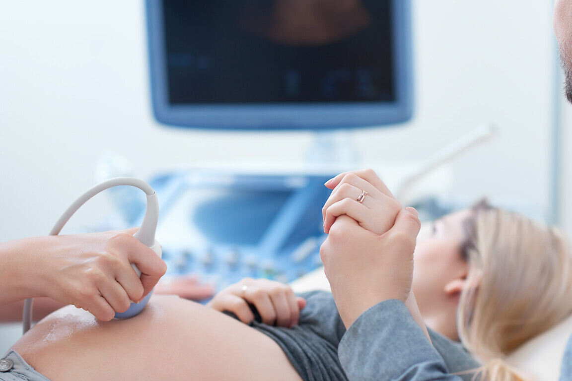 Husband holding hand his wife during ultrasound diagnostic.