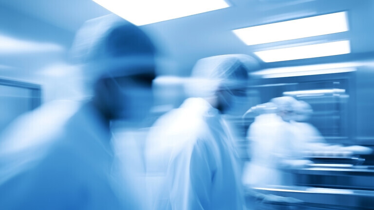 Motion blur of medical professionals in a hospital corridor, conveying urgency and fast-paced healthcare environment