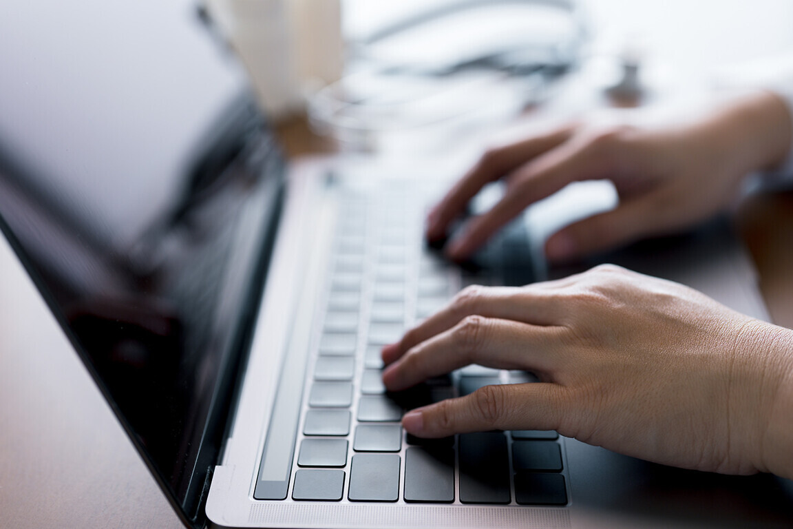 Close-up hands of doctor typing on laptop keyboard