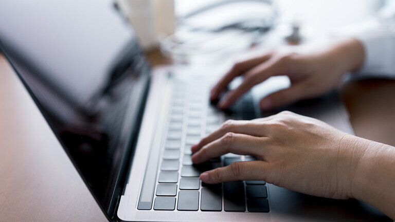 Close-up hands of doctor typing on laptop keyboard