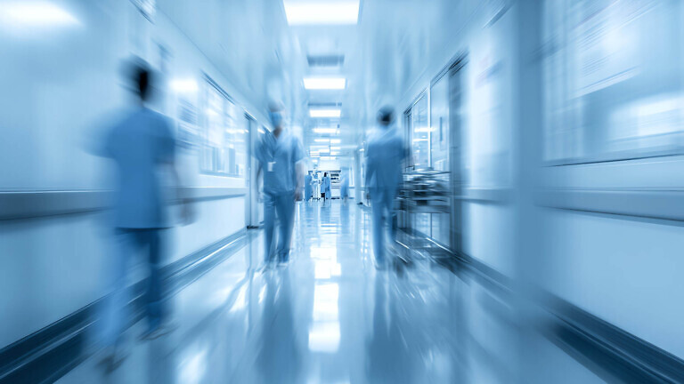 Blurred background of a hospital interior with medical equipment and people in motion Blurred hospital corridor with medical staff.