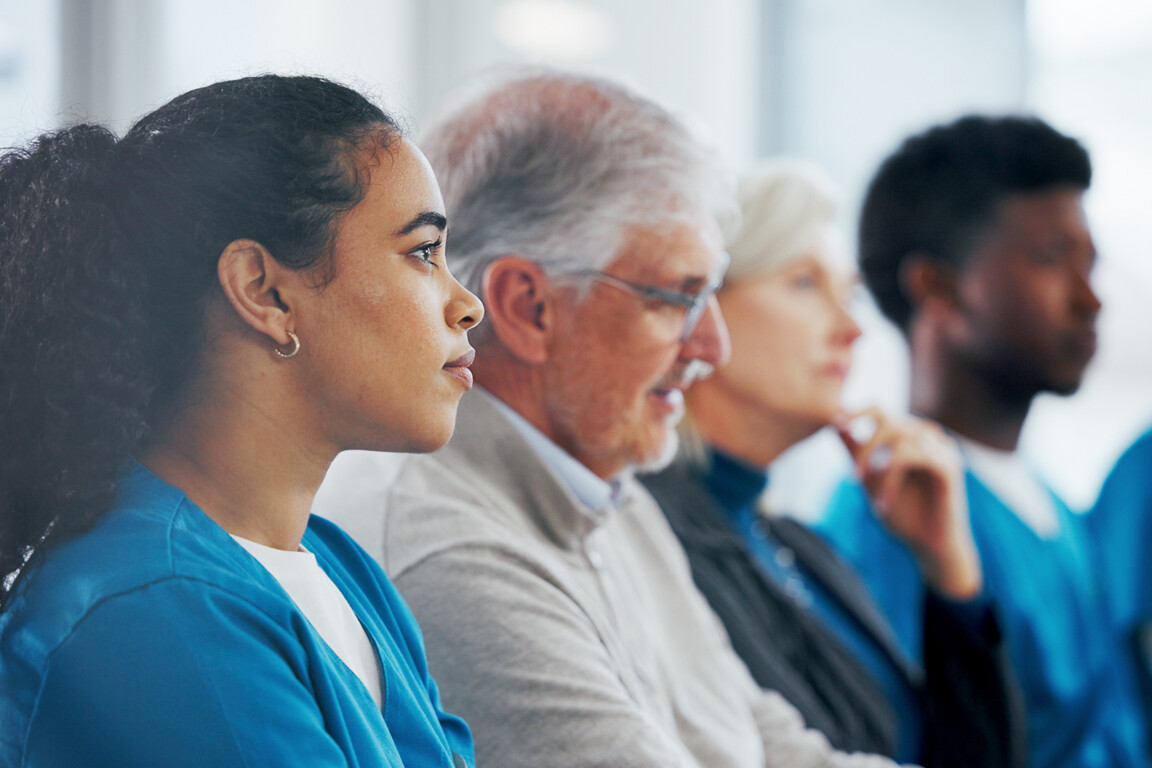 People, meeting and listening with medical team in seminar for presentation, workshop or conference. Group, employees or healthcare workers in row or line for staff training or development in clinic.