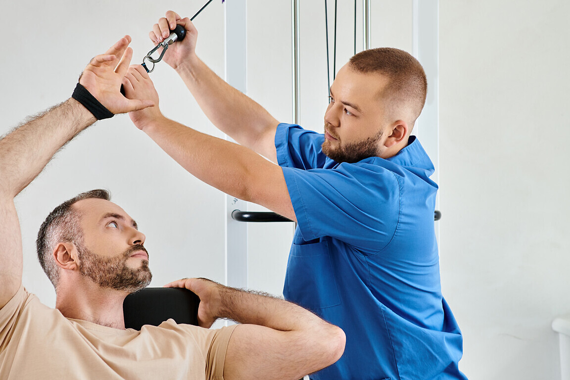skilled physician helping man in with recovery training