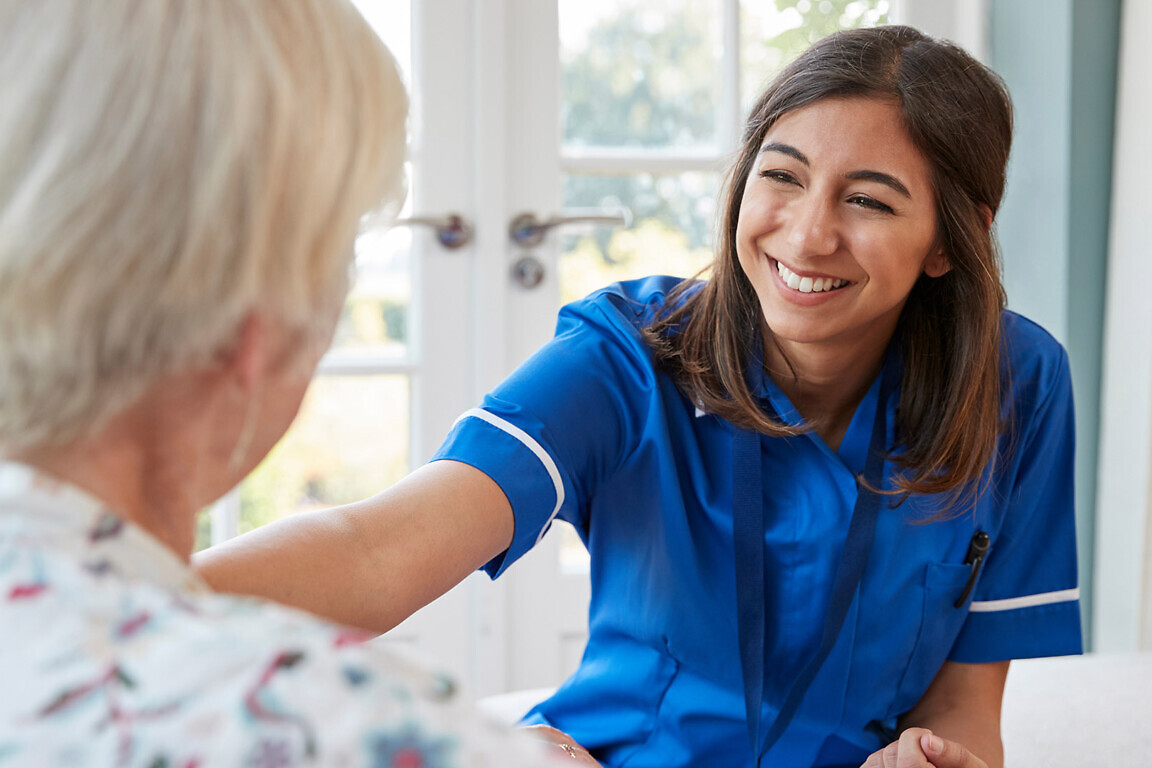 Young care nurse on home visit comforting senior woman