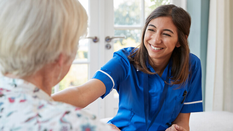 Young care nurse on home visit comforting senior woman