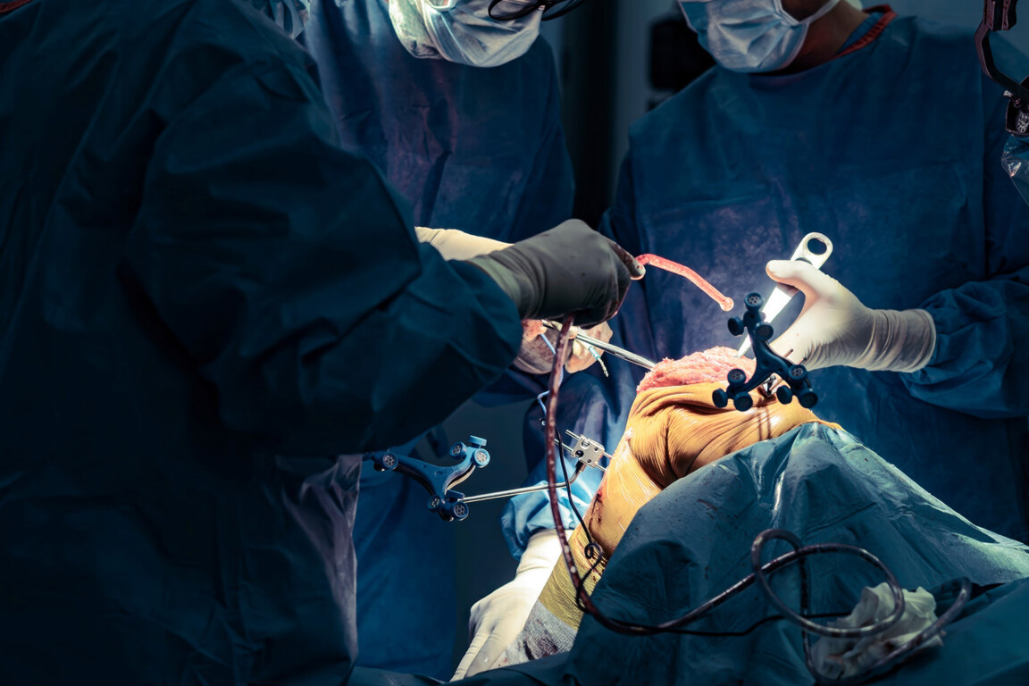Surgeons in scrubs use robotic assistance to perform a knee replacement.