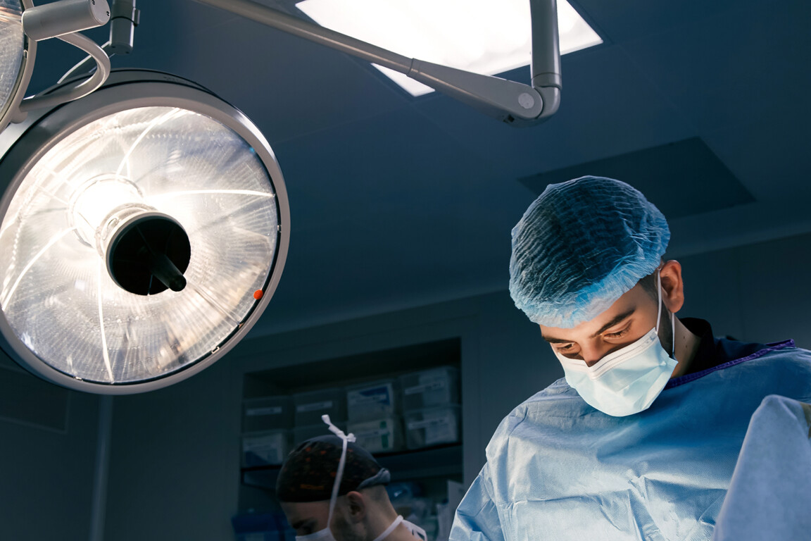 Male surgeon in blue surgical attire, focused on patient care.