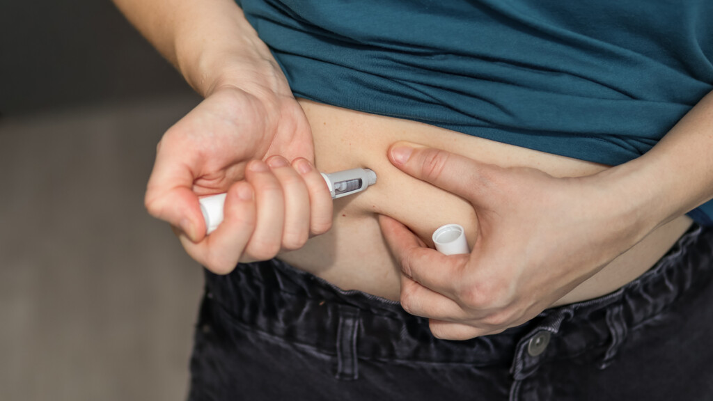 Injecting GLP-1 pen into abdomen.
