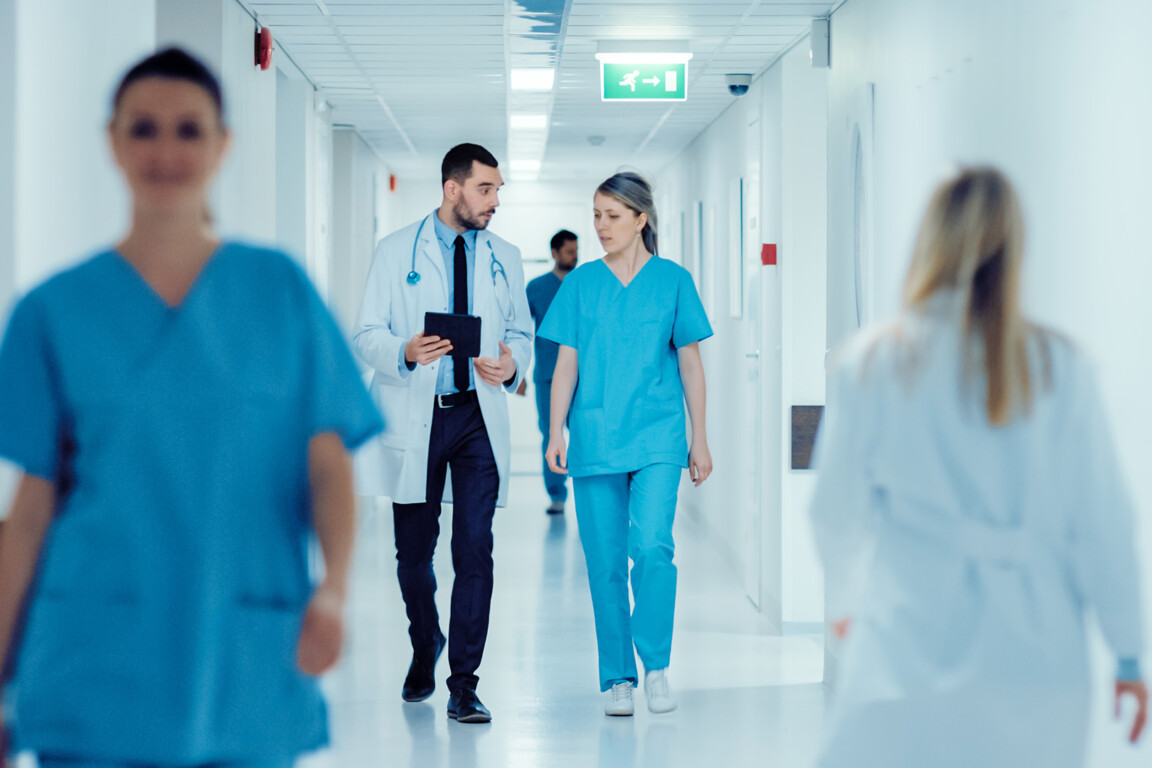 Surgeon and Doctor Walk Through Hospital Hallway.