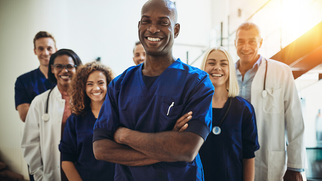 Smiling African doctor standing in a hospital with his staff