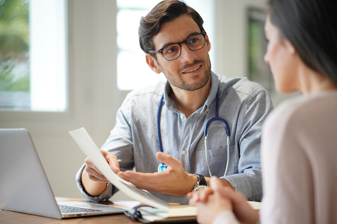 Modern young doctor speaking to patient in office