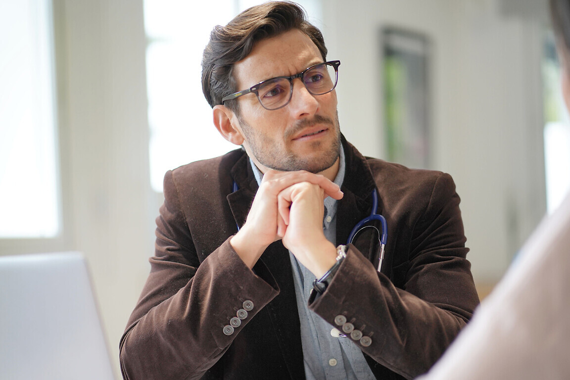 Modern young doctor speaking to patient in office