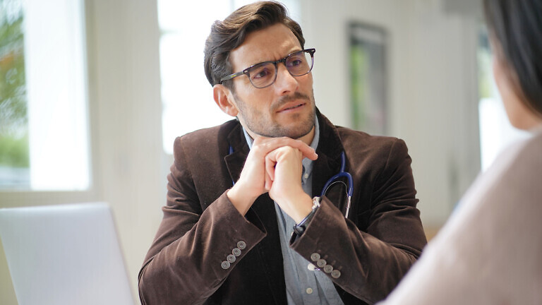 Modern young doctor speaking to patient in office