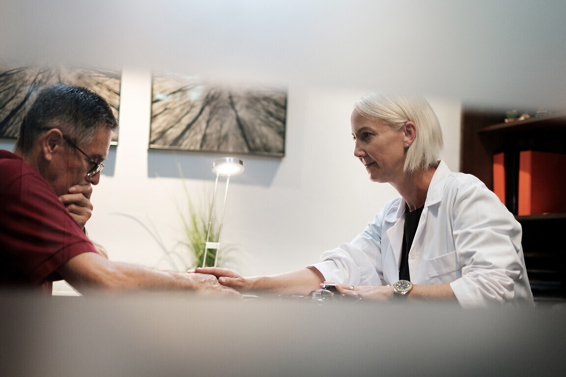 Moment when empathic female doctor communicates bad health news to senior patient at clinic consultation. Compassionate geriatric specialist explains medical situation to scared old man