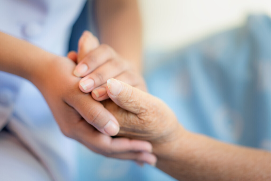 Nurse sitting on a hospital bed next to an older woman.