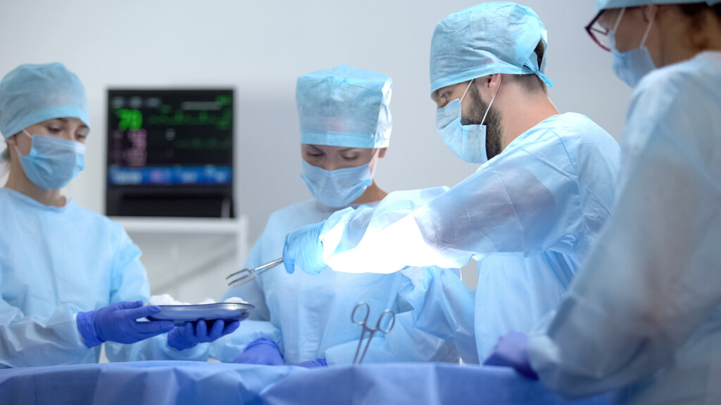 Assistant giving surgeon sterile medical equipment, invasive hos