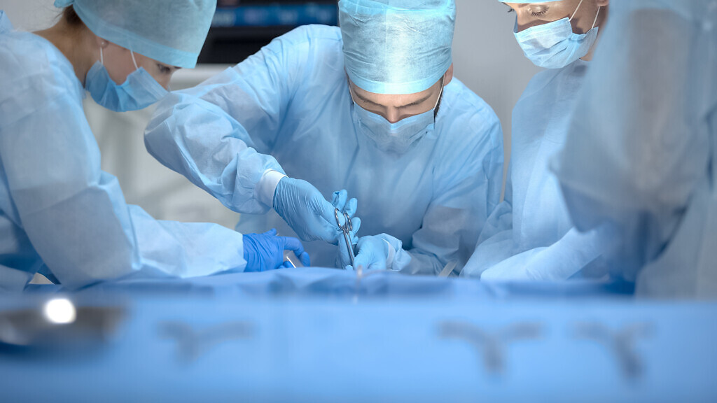 Professional surgeon team performing operation, sterilized instr