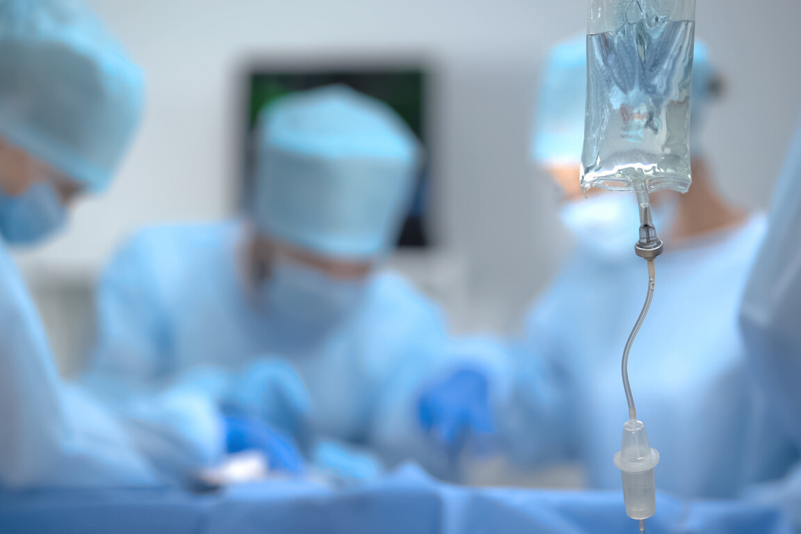 Medical drip bag on background of surgeon team working in operat