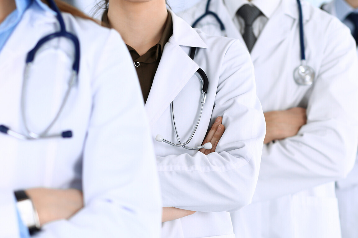 Group of modern doctors standing as a team with arms crossed in hospital office. Physicians ready to examine and help patients. Medical help, insurance in health care, best desease treatment and medicine concept