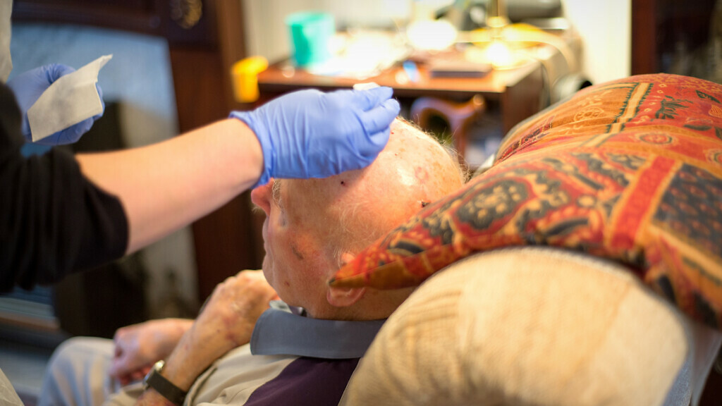 Elderly man being treated at home by a district nurse.