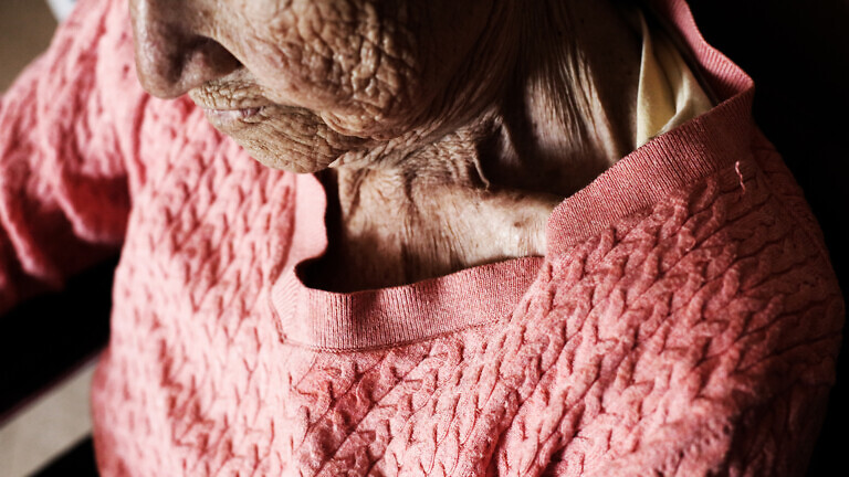 Aged woman sitting in wheelchair. wrinkle skin.