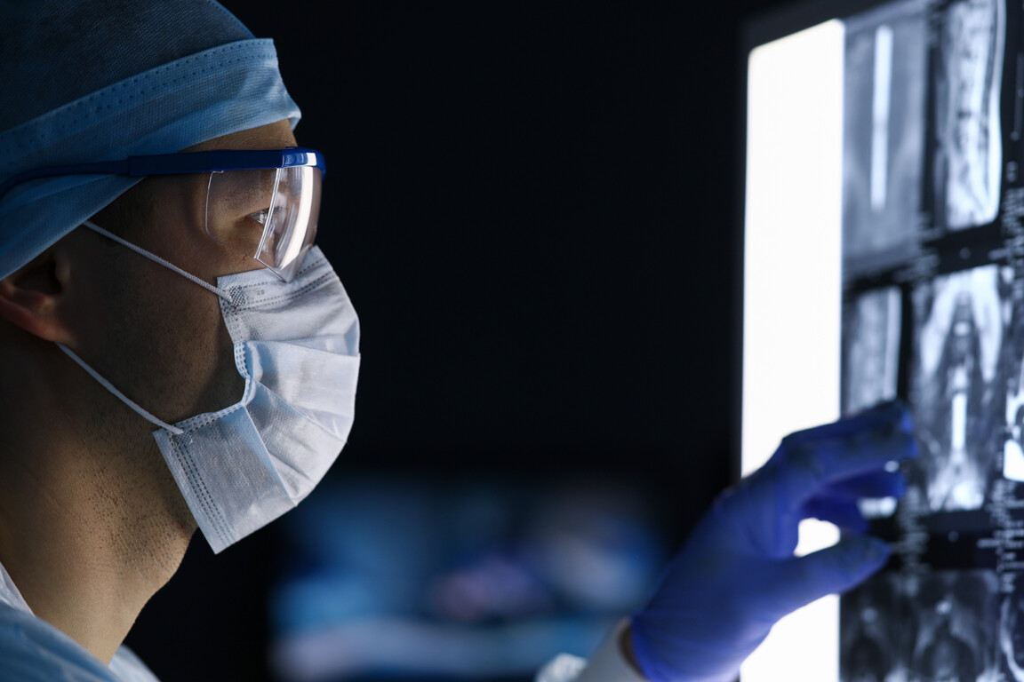 Male doctor in surgical clothes looking at vertebral mri scan