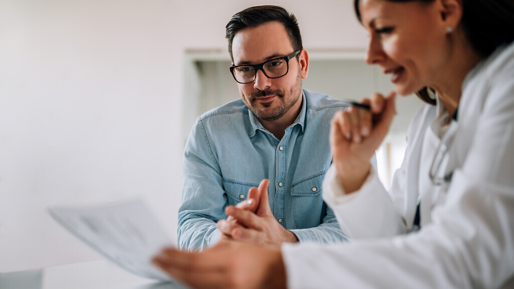 Close-up image of smiling man listening to a female healthcare 