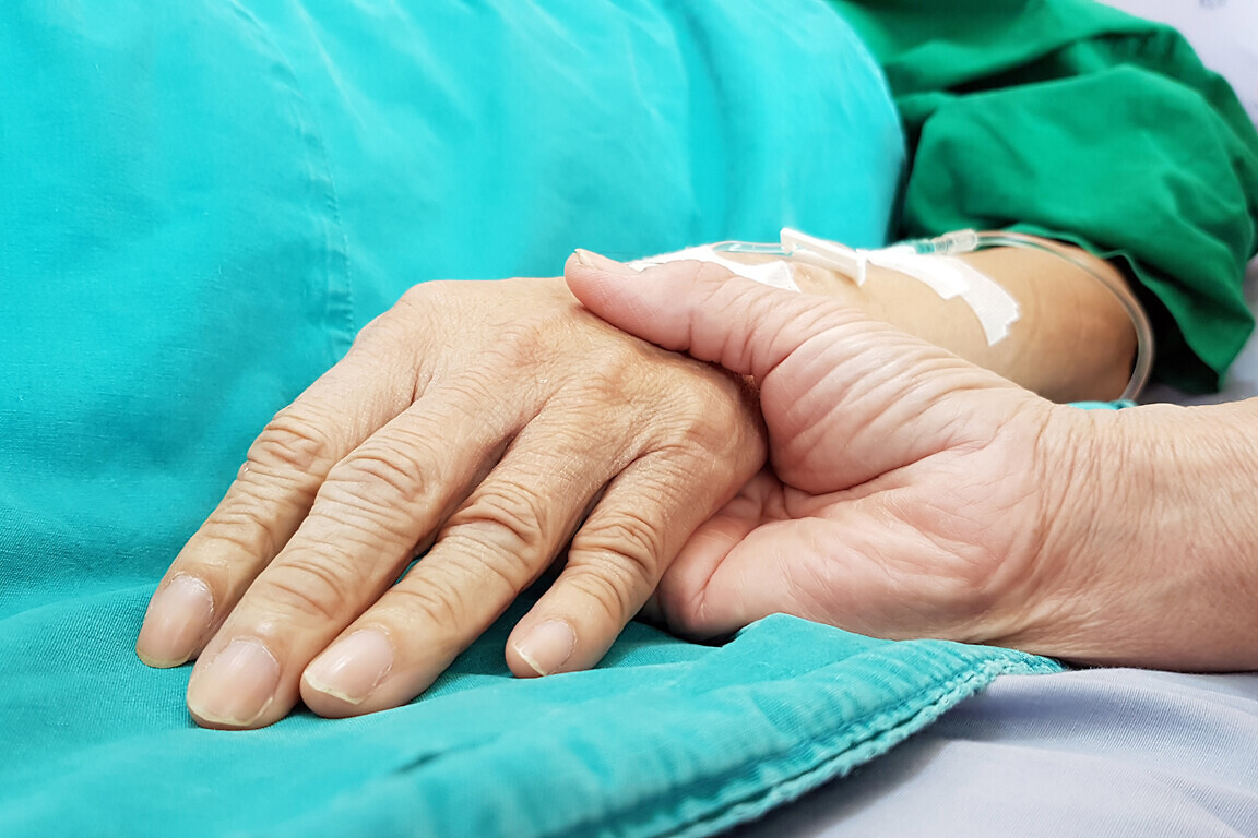 Oncologist doctor holding patient's hand in hospital.