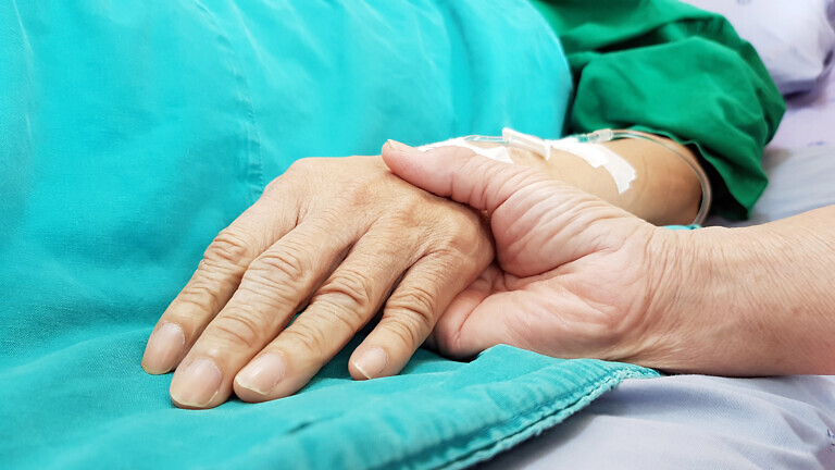 Oncologist doctor holding patient's hand in hospital.