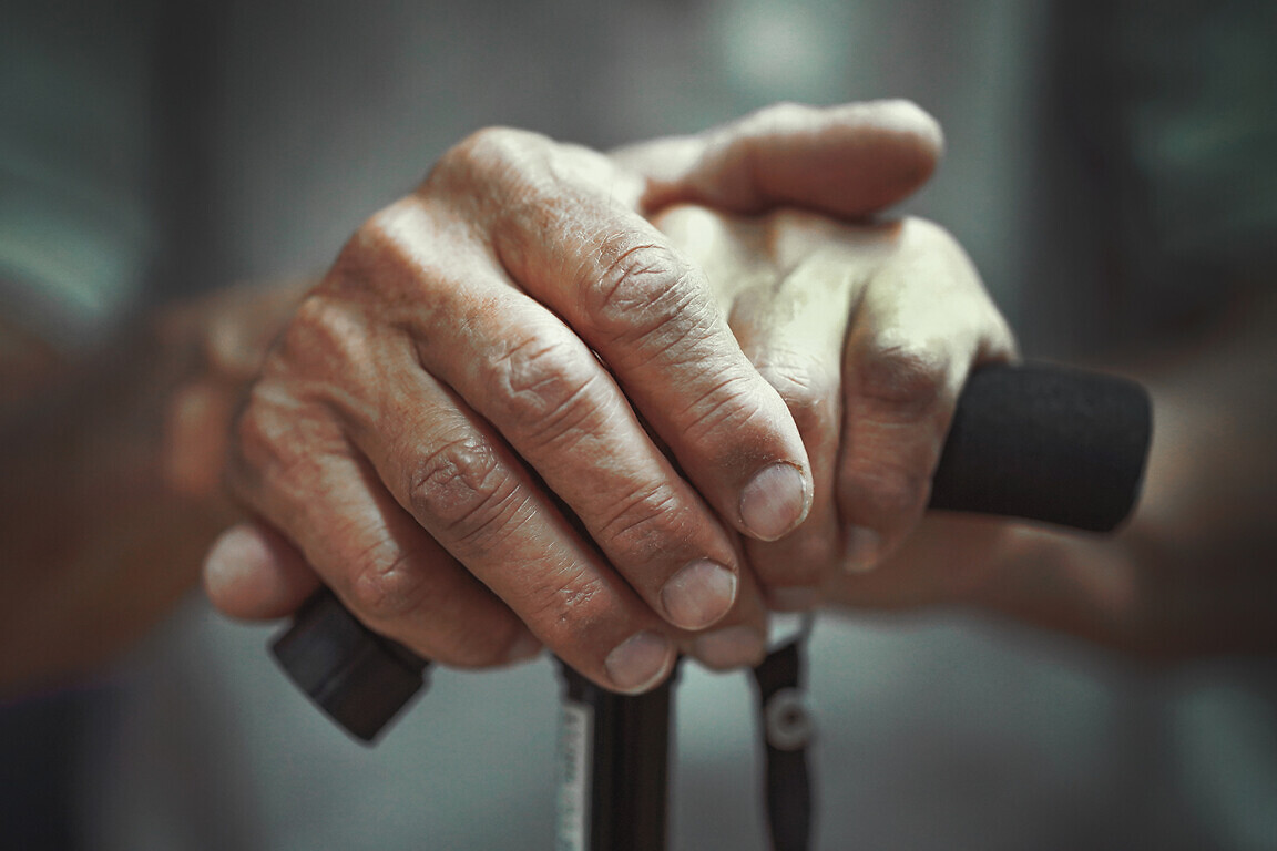 Hands of a senior man holding a cane.
