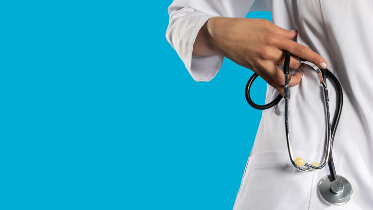 Stethoscope in a hand held by a young GP.