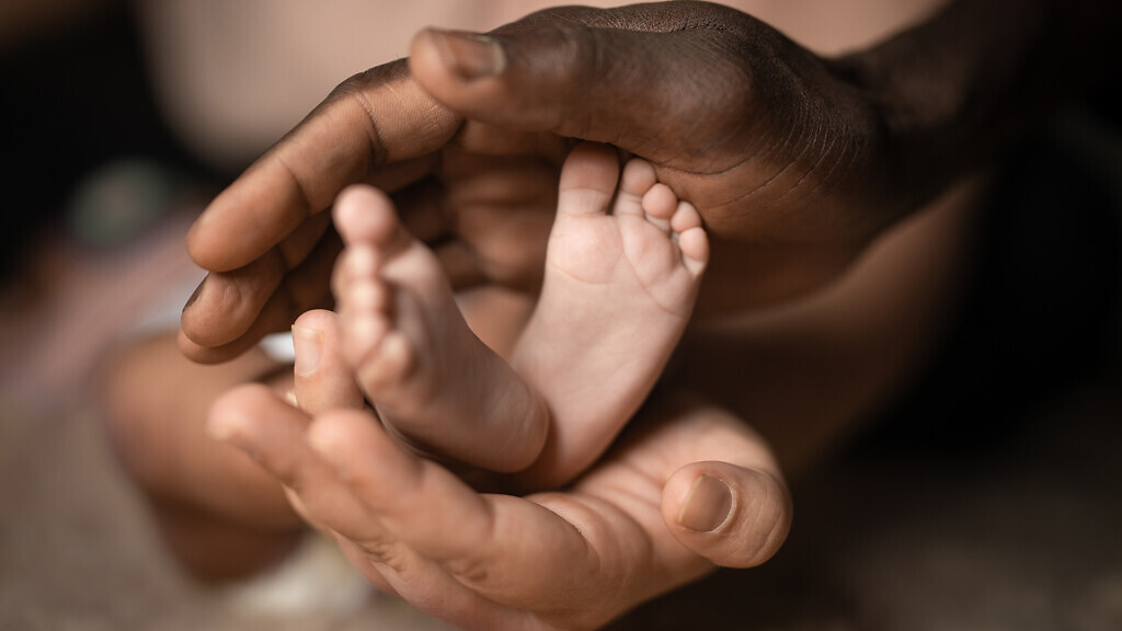 interracial family holding baby feet in hands mixed by black and
