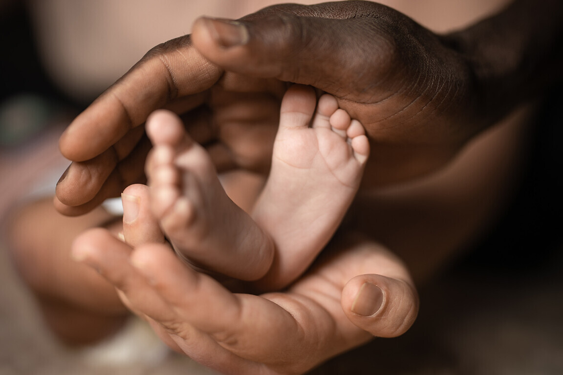 interracial family holding baby feet in hands mixed by black and