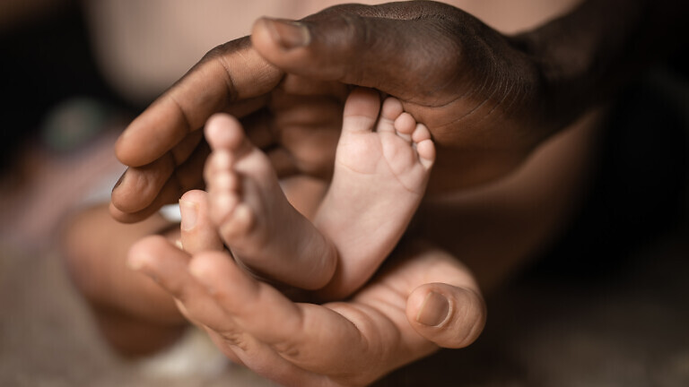 interracial family holding baby feet in hands mixed by black and