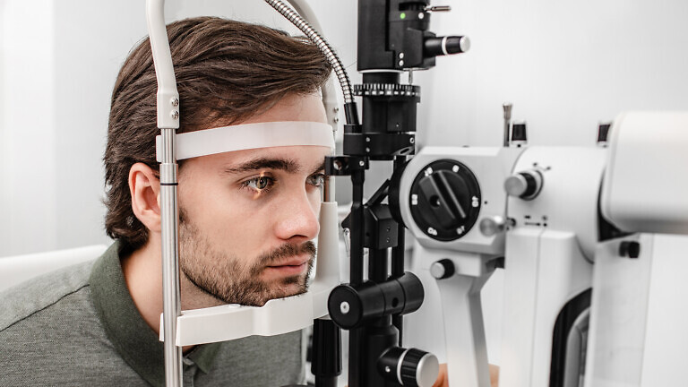 Adult man getting an eye exam at ophthalmology clinic.